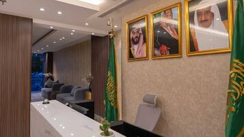 A modern reception area with a marble counter, framed portraits, and a green flag.