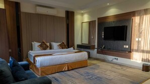 Camera d'albergo moderna con un letto grande, una TV a parete e un pavimento in legno.