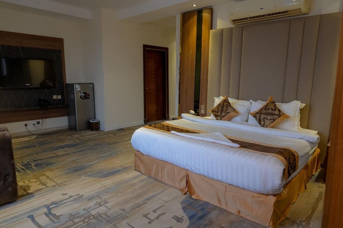 Une chambre d’hôtel avec un grand lit, une télévision, un minibar et un plancher en bois.