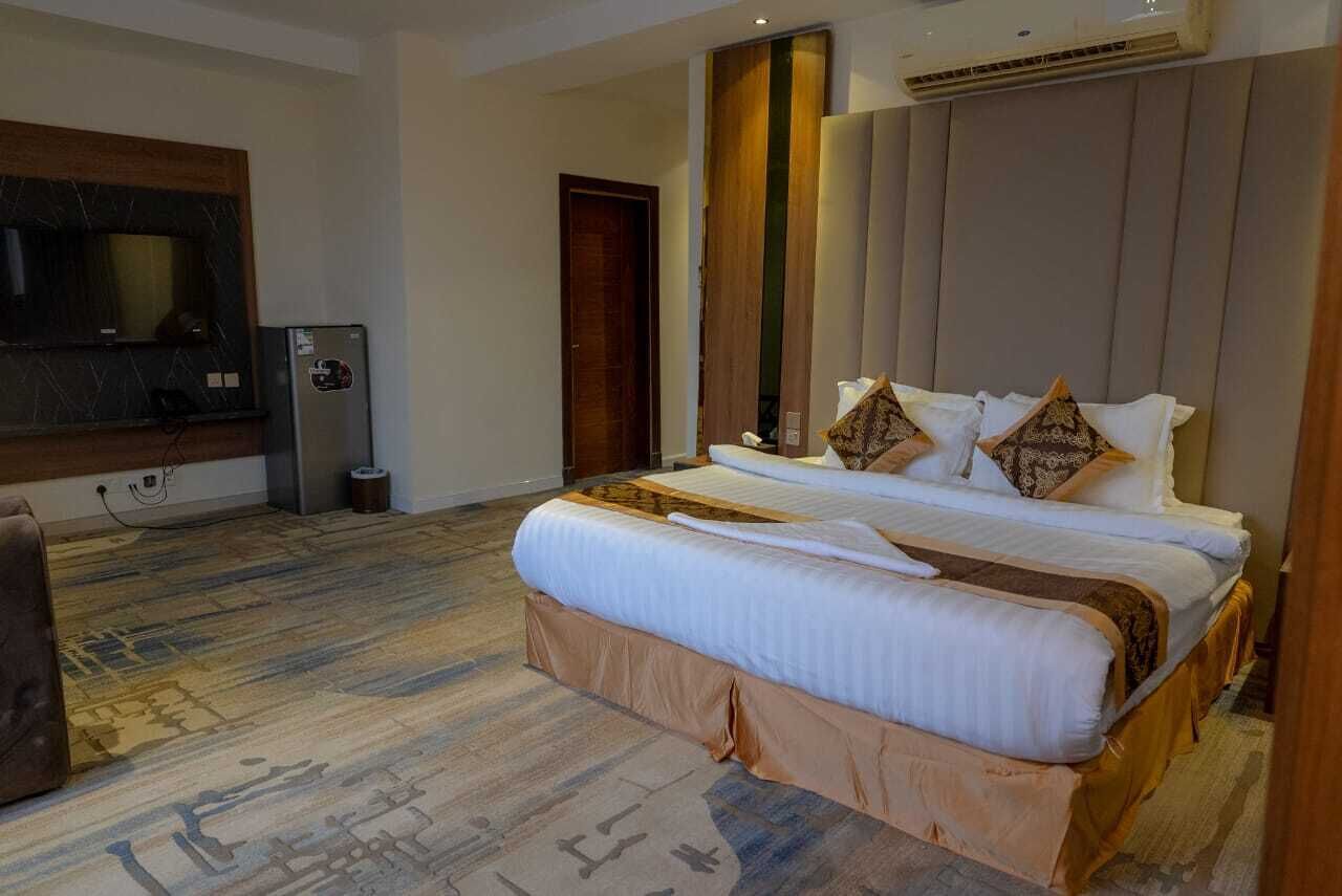 Ein Hotelzimmer mit einem großen Bett, einem Fernseher, einer Minibar und Holzboden.