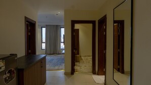 Un corridoio d'albergo con una reception, porte in legno e un grande specchio.