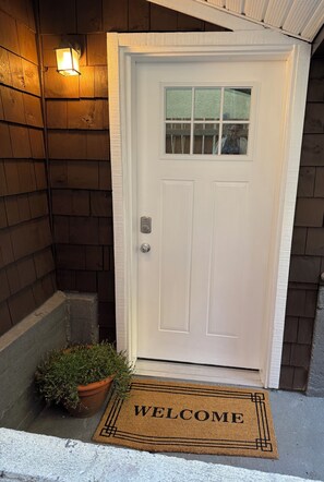 A white door with a glass panel, a welcome mat, and a potted plant beside it. - Lovely & Cozy suite near Save on Foods Arena and Downtown Victoria! (Victoria)