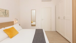 A bedroom with a bed, a bedside lamp, a mirror, a wardrobe, and a wall-mounted air conditioner. - Rental in Rome Mastai Trastevere Home (Rome)