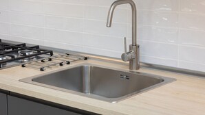 A modern kitchen with a stainless steel sink, a gas stove, and a sleek faucet. - Rental in Rome Mastai Trastevere Home (Rome)