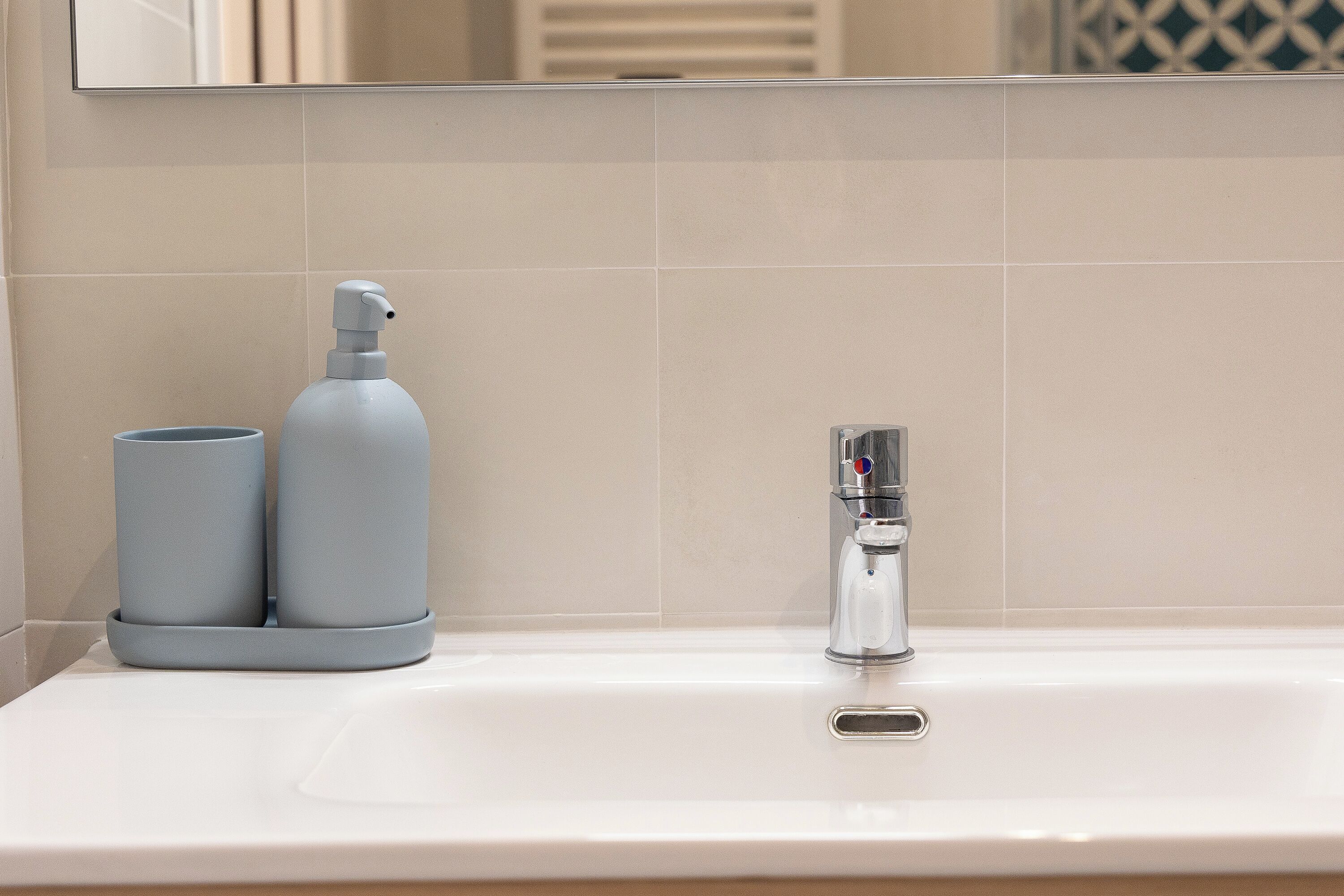 A bathroom sink with a modern faucet, a soap dispenser, and a cup.