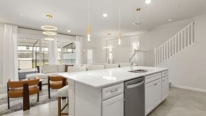 A modern kitchen with a central island, white cabinetry, and a stainless steel sink. - 5 Bd / 4,5 Ba / Sleeps 14 / Windsor Cay Resort (Clermont)