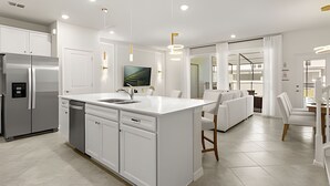A modern kitchen with white cabinetry, a central island with a sink, and a built-in refrigerator. - 5 Bd / 4,5 Ba / Sleeps 14 / Windsor Cay Resort (Clermont)