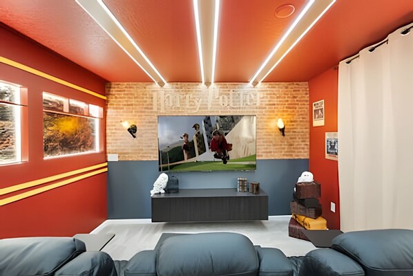 Un moderno cine en casa con una pared de acento de ladrillo, un televisor grande y un mueble multimedia oscuro.