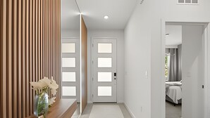 A hallway with two doors, a wooden panel wall, and a bed visible through an open door. - 7 Bd / 6.5 Ba / Sleeps 20 / Solara Resort (Kissimmee)