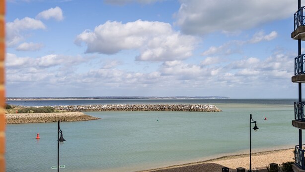 A coastal view with a pebbled beach, a stone breakwater, and a clear sky. - Harbour Hideaway - great views & flexible beds (Eastbourne)