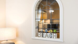 A window with the word "BEACH" spelled out in wooden letters, a lamp, and a view of a kitchen area. - Harbour Hideaway - great views & flexible beds (Eastbourne)