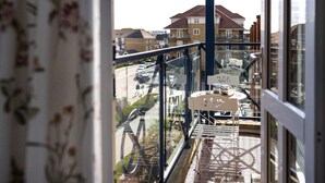 A balcony with a table and chairs, overlooking a street with parked cars and buildings. - Harbour Hideaway - great views & flexible beds (Eastbourne)