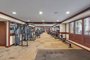 A gym with various exercise equipment, a central aisle, and windows on one side. - Spacious 2BR/2BA Oceanfront Villa in Ko Olina Beach Tower with Lagoon Views (Kapolei)