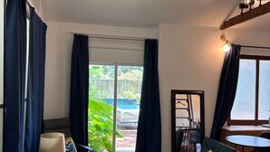 A modern living room with a sofa, a small table, a chair, and a large window. - Pecan Pool House  - Garden Villa #2 (Houston)