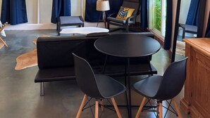 A modern room with a large window, a round table, and a sofa. - Pecan Pool House  - Garden Villa #2 (Houston)