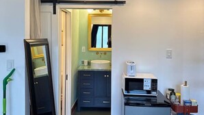 A narrow hallway with a mirror, a refrigerator, and a microwave. - Pecan Pool House  - Garden Villa #2 (Houston)