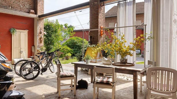 Une terrasse avec une table, des chaises, un pot de fleurs et un vélo.