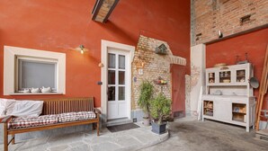 Un espace extérieur accueillant, aménagé avec un banc, une plante en pot et un meuble blanc doté d’étagères.