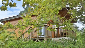 A wooden cabin with a balcony, surrounded by dense foliage. - Beautiful apart for 4 pers in the forest (Parentis-en-Born)