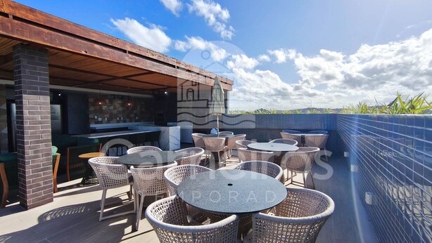 An outdoor patio with wicker tables and chairs, a bar area, and a view of the sky. - Makani Beach Campas - Praia de Tamandaré (Tamandaré)