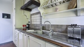 Een keuken met een dubbele spoelbak, een broodrooster en een plank met servies.