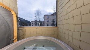 Een bubbelbad in een hoek met uitzicht op een woongebied en bergen op de achtergrond.