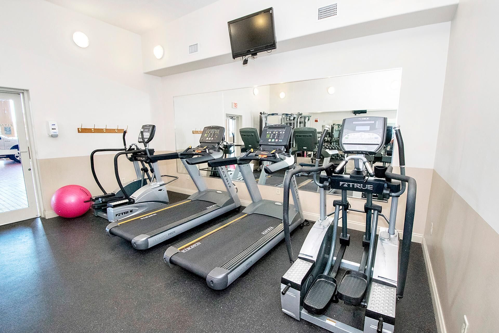 Ein Fitnessstudio mit Laufbändern, Crosstrainern und einem Ergometer.