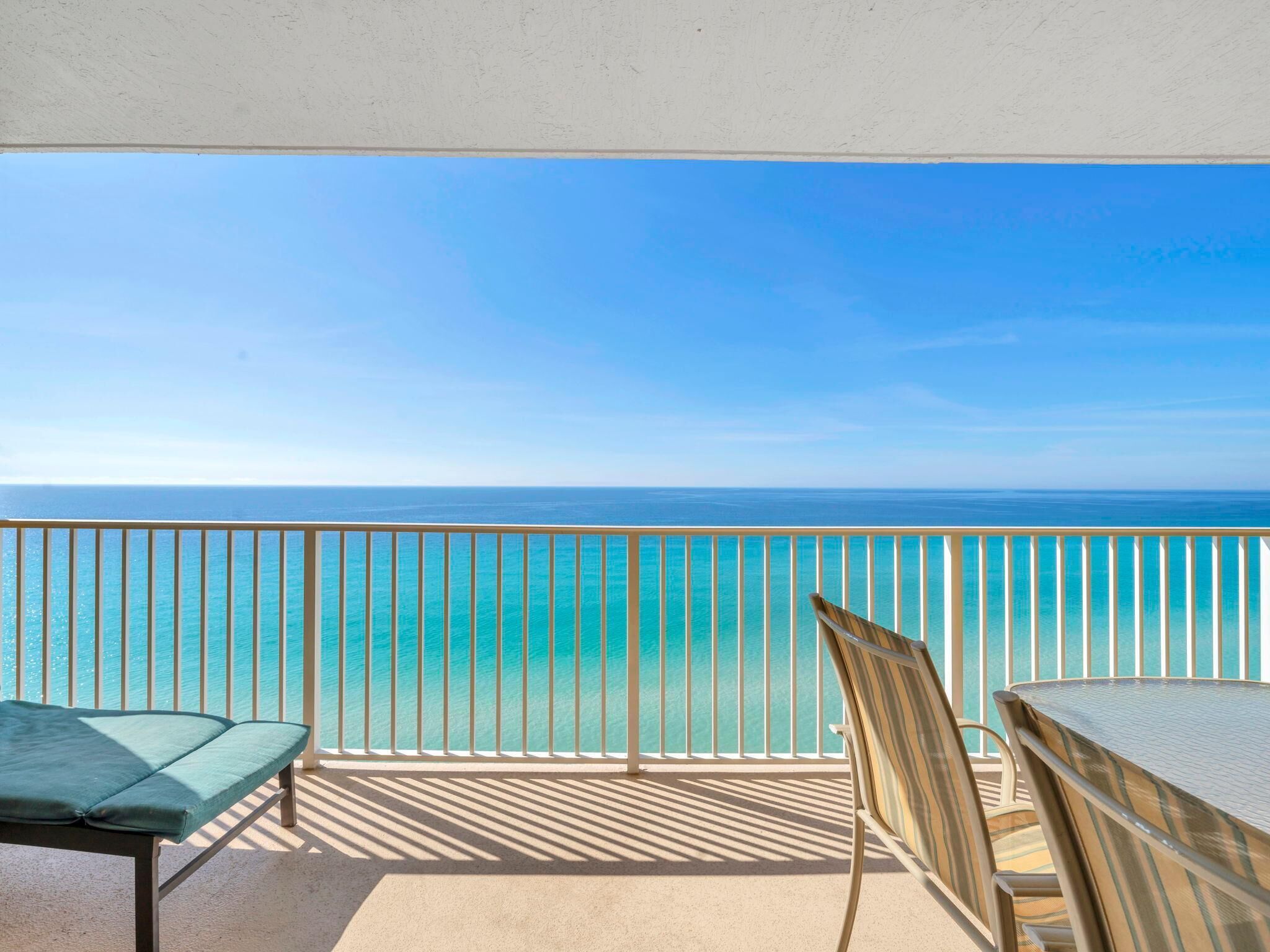 Uma varanda com vista para o oceano, uma mesa e uma cadeira.