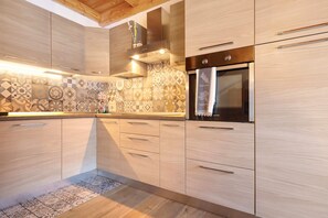 Eine moderne Küche mit hellen Holzschränken, einem gemusterten R ücksprung, Edelstahlgeräten und einem Holzboden.