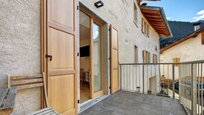 A building with a wooden door, a bench, and a tiled patio.