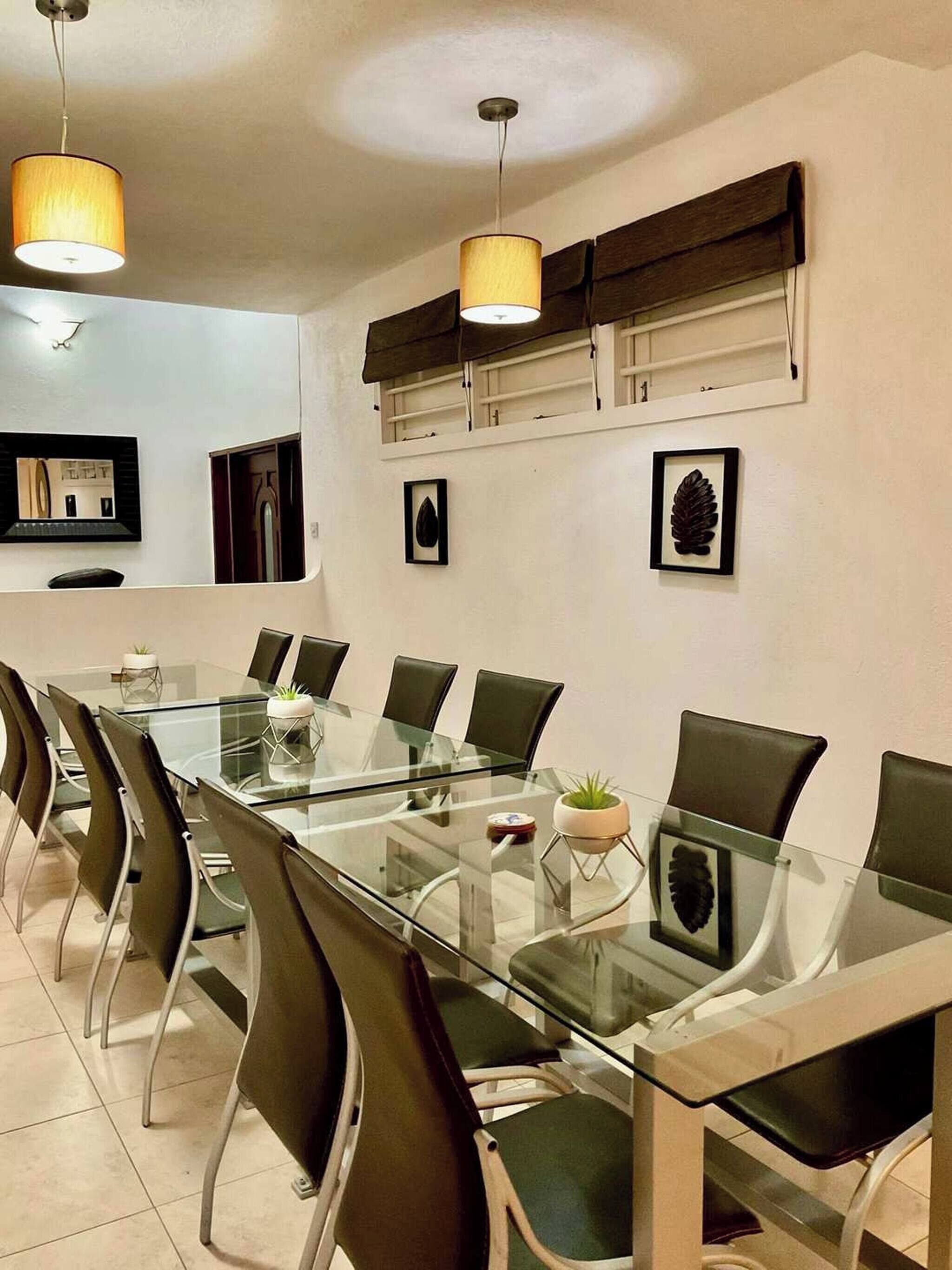 A modern meeting room with a glass table, black chairs, and two pendant lights.