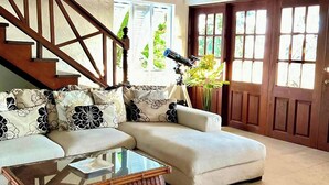 A living room with a sofa, a glass coffee table, a telescope, and a staircase. - Harbour View - by Zenbreak (Lodge Hill)