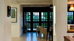 A spacious hallway with a large orange pendant light, a dining area with a table and chairs, and a view through large windows to the outdoors. - Harbour View - by Zenbreak (Lodge Hill)