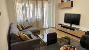 A modern living room with a sofa set, a glass coffee table, and a flat-screen TV mounted on the wall. - Centro Lecco [Dante Avenue]: Lake & Mountains (Lecco)