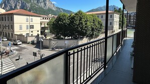 A balcony with a view of a mountain, buildings, and a tree. - Centro Lecco [Dante Avenue]: Lake & Mountains (Lecco)
