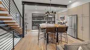 A modern kitchen with a wooden dining table, chairs, and a stainless steel refrigerator. - Luxury 3BR Townhome with W/Private Spa 1089 (Steamboat Springs)