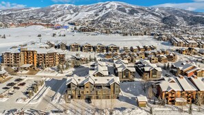 A snow-covered resort with multiple buildings, a ski slope in the background, and a clear blue sky. - Luxury 3BR Townhome with W/Private Spa 1089 (Steamboat Springs)