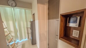 Una cocina con refrigerador, un reloj y una estantería de madera con un microondas.