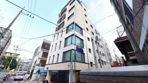 Un edificio de varios pisos con un letrero azul que indica un negocio en la planta baja.