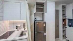 Una cocina con un refrigerador de acero inoxidable, una tetera y un lavamanos.