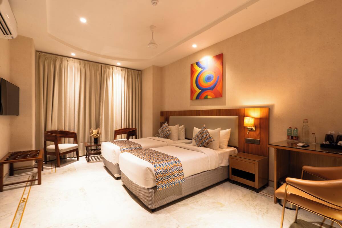 A hotel room with a large bed, a desk, a chair, and a painting on the wall.