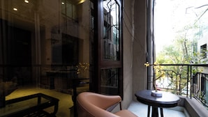 A modern interior with a leather chair, a small round table, and a view of the outside through a large window. - Hotel Bluestone Prime Nehru Place by The Cosy hotels (New Delhi)