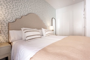 A neatly made bed with striped pillows, a bedside table, and a nightstand. - Genteel Home Zabaleta I (Madrid)