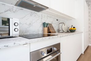 Una cocina moderna con microondas integrado, un reloj digital y un horno de acero inoxidable.