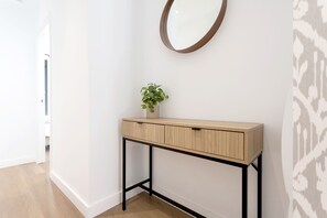Un couloir avec une console en bois, une plante en pot et un miroir accroché au mur.