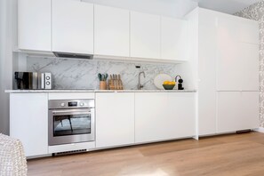 A modern kitchen with white cabinetry, a built-in oven, a microwave, and a sink with a faucet. - Genteel Home Zabaleta I (Madrid)