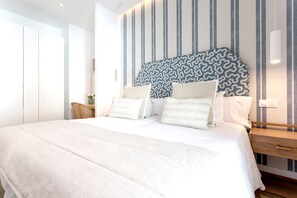 Une chambre à coucher moderne avec un grand lit, une tête de lit à motifs et une table de chevet avec une lampe.