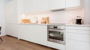 Een moderne keuken met witte kastjes, roestvrijstalen apparatuur en een houten snijplank.