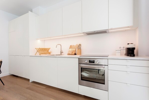 A modern kitchen with white cabinetry, a stainless steel oven, and a coffee maker. - Genteel Home Zabaleta II (Madrid)