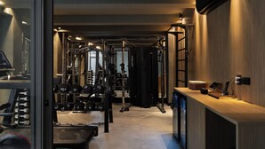 A modern gym with various exercise equipment, a wooden reception desk, and a large mirror. - Íz Hotel Conceito (Goiânia)